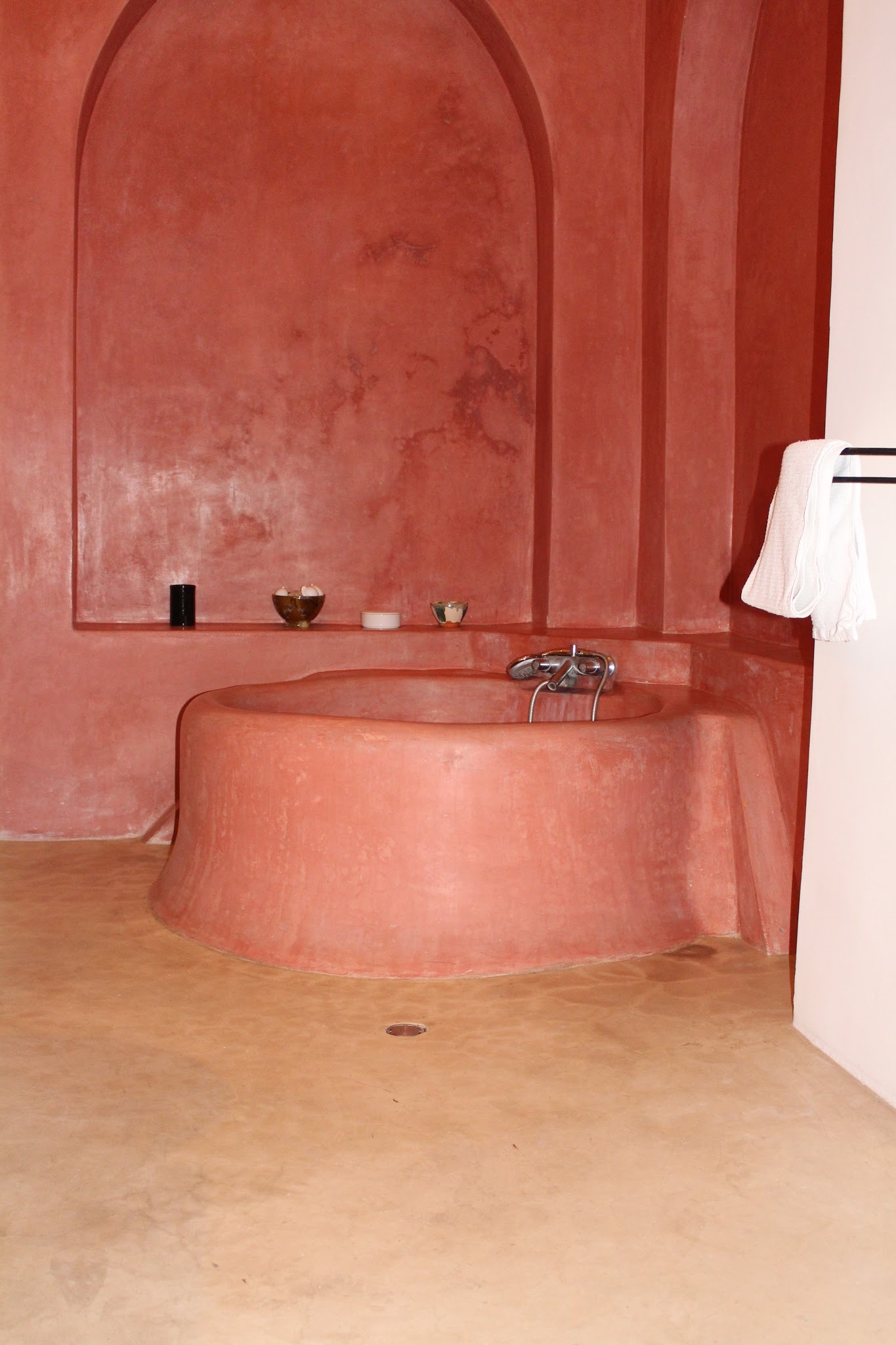 Salle de bain en tadelakt rose avec baignoire maçonnée sous une niche en arc